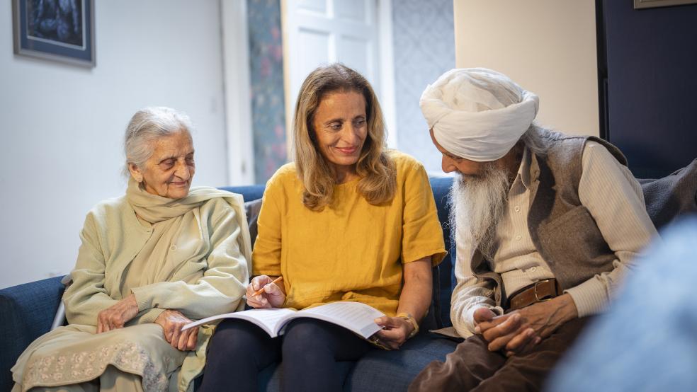 older woman, older man and younger woman of south asian origin sitting and talking
